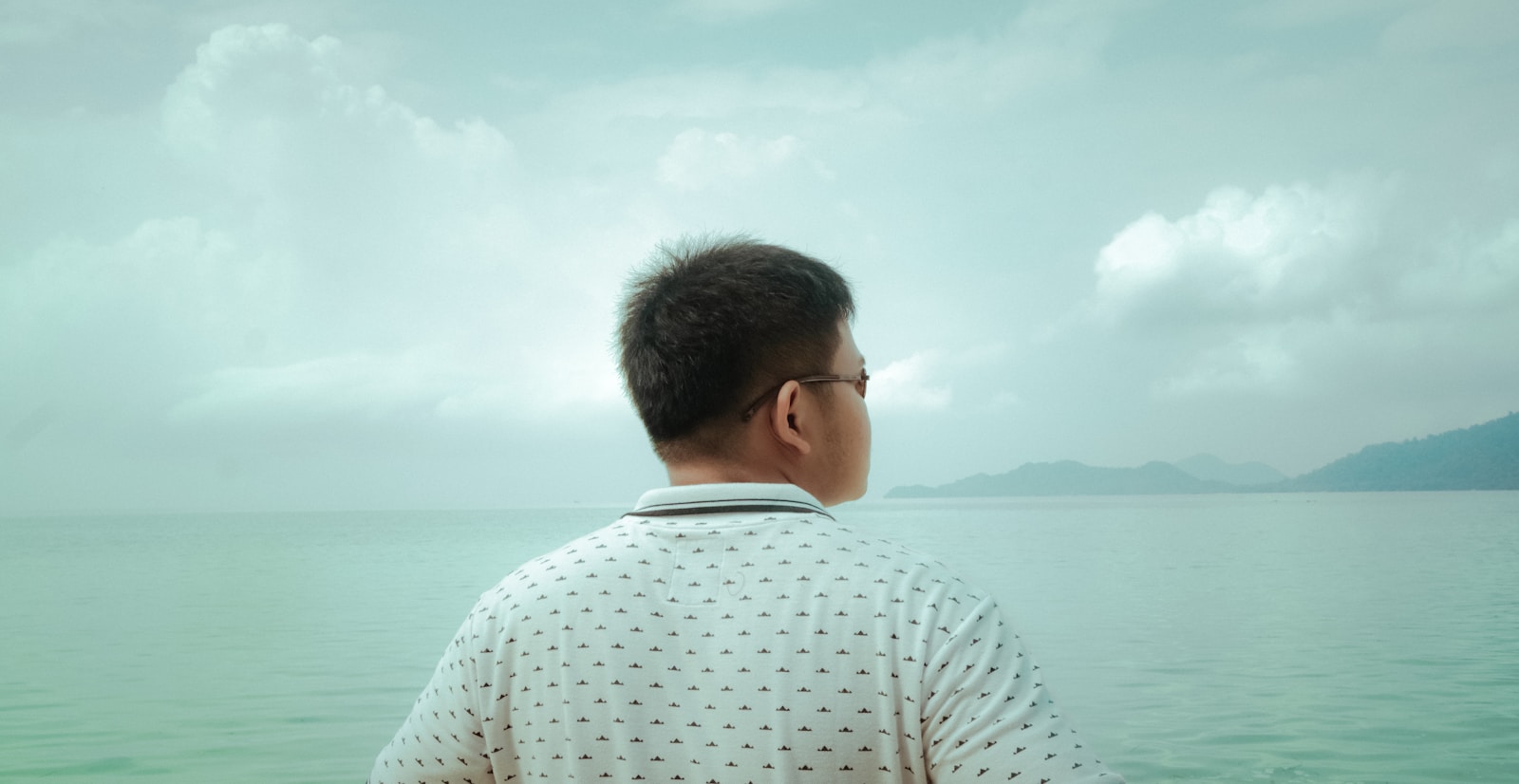 man in white and black checkered dress shirt looking at the sea during daytime